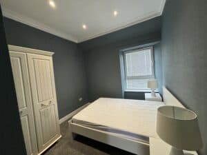 A nice bedroom with dark green walls and LED spotlights and a wardrobe